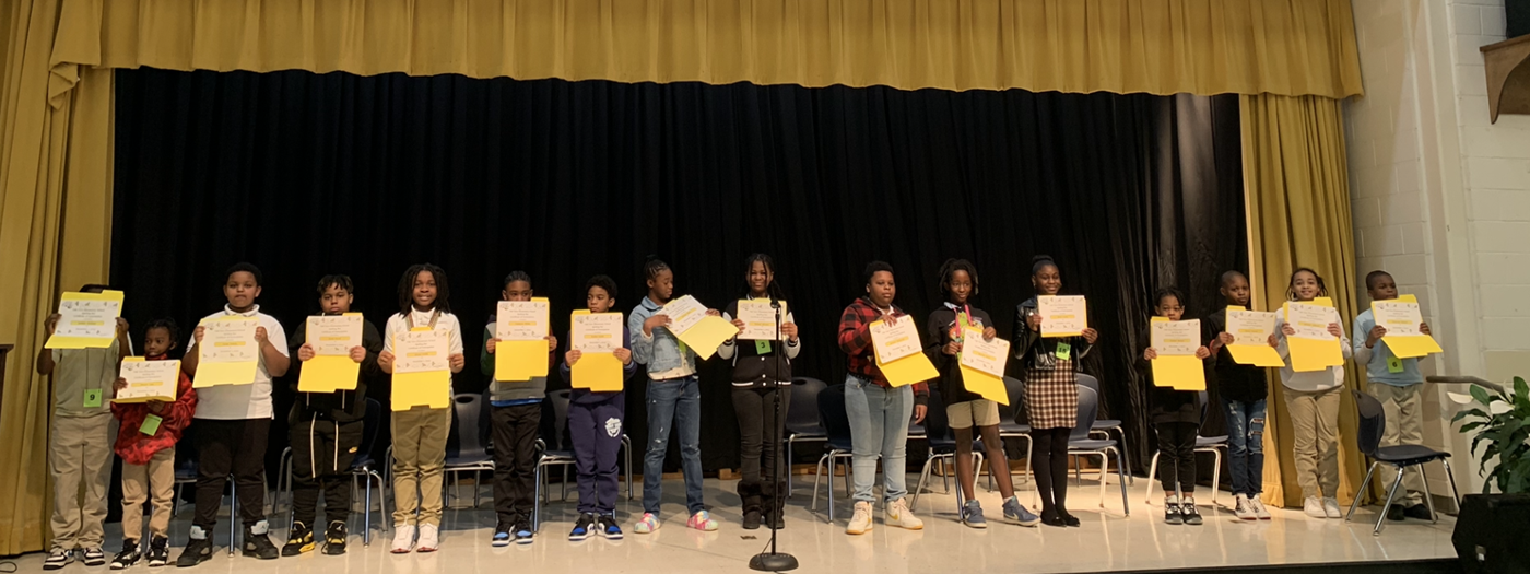 The Spelling Bee Contestants pose on stage with their certificates